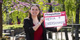 Image of Sydney Binkley holding a sign that reads "media & entertainment."