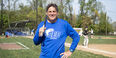 Image of a person wearing a blue shirt and holding up baseball bat on a field.