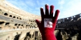  A hand wearing a Temple glove in front of the Colosseum in Rome.