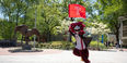 Hooter carries the Temple flag as he runs past the owl statue and points at the camera