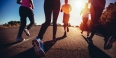 Four people’s legs as they jog on a street.