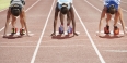 Women runners kneeling on the track before a race starts. 