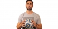 A male Temple soccer player wearing a gray T-shirt and holding a soccer ball.