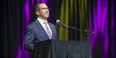 Jose Aviles in a suit at a podium