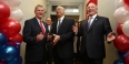 Three men smiling as they cut the ribbon at the veteran center.