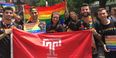 Students and alumni carrying a rainbow Pride flag and a Temple Flag.