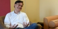 Roger Ideishi smiling and sitting in a chair. 