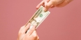 Hands pulling a twenty dollar bill from opposite end