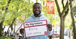 Andrew Ankamah holding a sign that says ending gun violence.