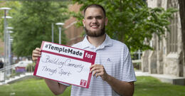 Ezekiel Cartwright standing outside holding up a Temple Made for sign    
