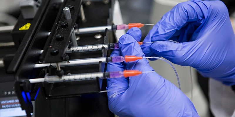 An engineering researcher adjusting vials in a lab.