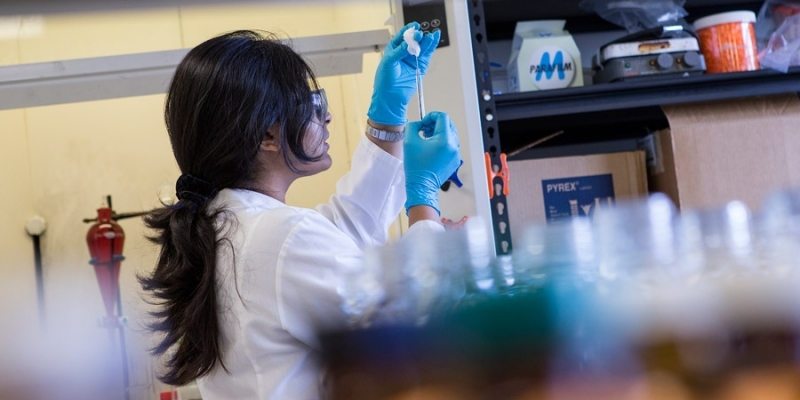 A female researcher cleaning a syringe in a lab.