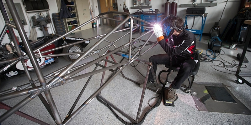 A Temple engineering students welds a portion of a race car.