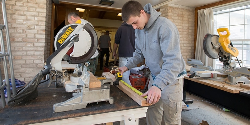 A student using a saw to build the Philadelphia Flower Show exhibit.
