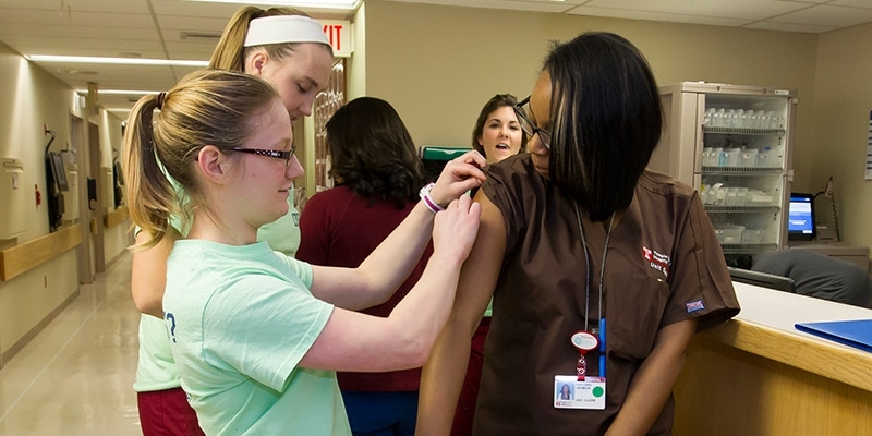 A member of the Flu Crew applying a bandage to an employee after a vaccination.