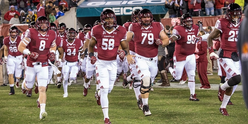 Temple football players running on to the field.