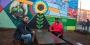 Two men sitting in front of a new colorful mural in North Philadelphia.
