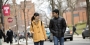 Two students talking to each other as they walk north on 12th Street on campus.