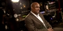 A man in a brown suit sitting in a recording studio.