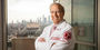 Dean Daly standing before a window with a view of the Philadelphia skyline.