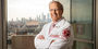 Dean Daly standing before a window with a view of the Philadelphia skyline.