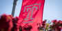 Temple flag flying above red flowers.