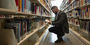 Image of student looking through bookshelves at Charles Library.