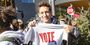 A Temple student holding a t-shirt that says vote