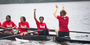 Image of children with smiles wearing red t-shirts, rowing a boat.  