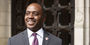 mage of Tony Thurmond in a suit and tie with an Owlmark lapel pin.