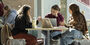 Three students at a table working on laptops