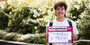 Image of Tran holding a sign that says “#TempleMade for travel and tech”