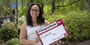 Trista Mayo standing outside holding up a Temple Made for sign