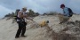 A man using a yellow georadar machine on a beach.