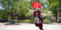 Hooter carries the Temple flag as he runs past the owl statue and points at the camera