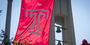 the Temple T flag waving in front of the bell tower on a clear, sunny day. 