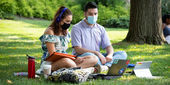 Two Temple students wearing masks study outside on Main Campus.