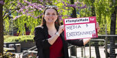 Image of Sydney Binkley holding a sign that reads "media & entertainment."