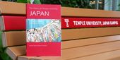 A copy of The History of Temple University Japan on a bench