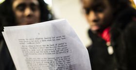 Two Black women read a page from a document together.