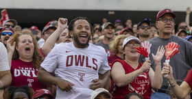 Image of a smiling college football fans wearing Temple-branded shirts.  