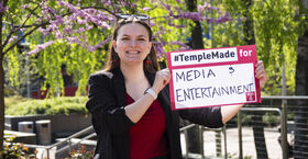 Image of Sydney Binkley holding a sign that reads "media & entertainment."