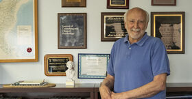 Phil Kendall stands in front of a bookshelf in his office 