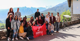  Mountains in the background, a group of Temple students holding a Temple cherry flag.