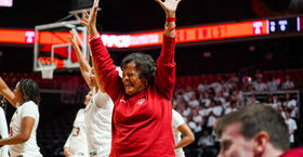  Image of Temple University’s Coach Diane Richardson smiling and raising her hands during a college basketball game.