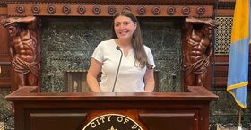 Giordano stands behind a podium in the mayor’s office