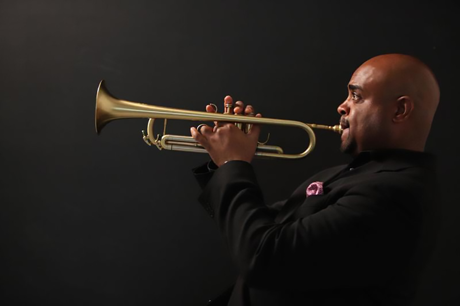 Terell Stafford playing the trumpet on a dark background