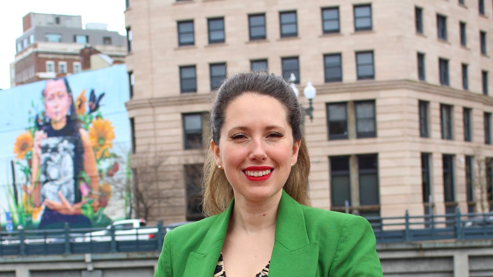 Natalia Ángeles Vieyra standing in front of a mural and building